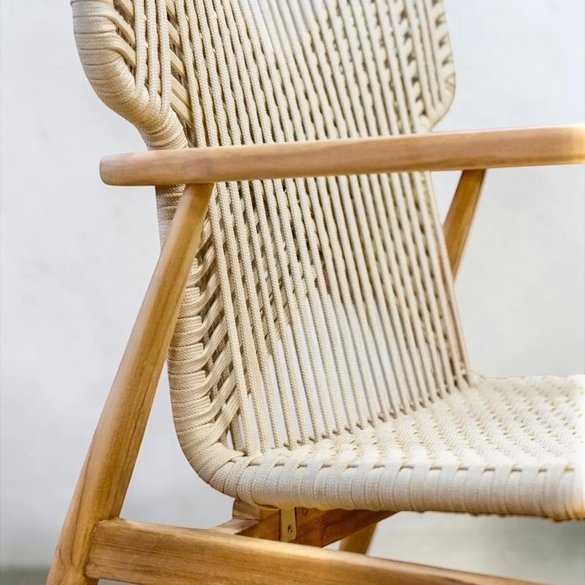 Fauteuil lounge Sumba en teck massif clair, dossier en cordage écru tressé en chevron, coussin lombaire sable